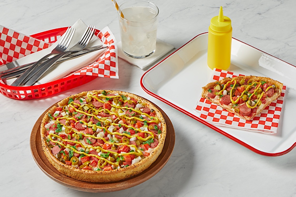 This photo shows a deep-dish pizza topped with hot-dog meat, onions, sliced jalapeños and other ingredients.
