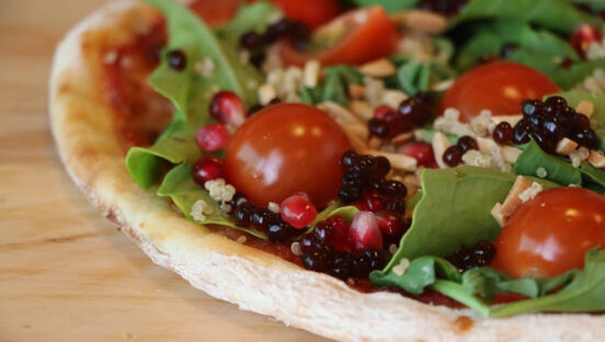 This photo shows a pizza with balsamic pearls on the edges near the crust.