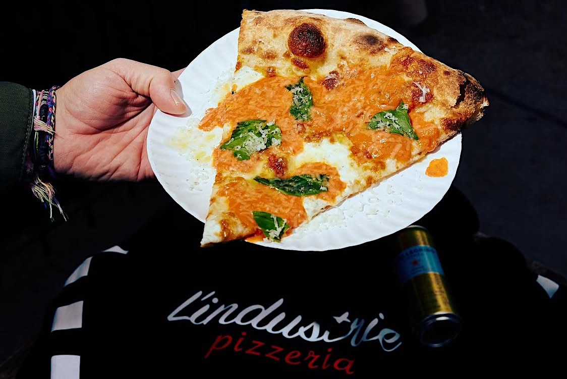This photo shows a slice of pizza with mozzarella, basil and a vodka sauce.