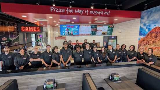 This photo shows a large group of Mountain Mike's employees standing behind the counter in a restaurant in Las Vegas.