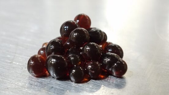 This photo shows a pyramid of beautiful dark Balsamic pearls against a white backdrop.