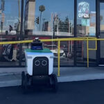 This photo shows a delivery robot parked in front of a Little Caesars location.