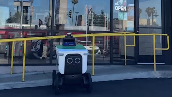 This photo shows a delivery robot parked in front of a Little Caesars location.