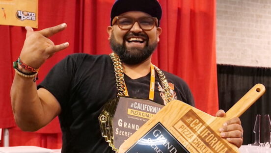This photo shows Juan Robles, dressed in black, holding his grand champion pizza peel.