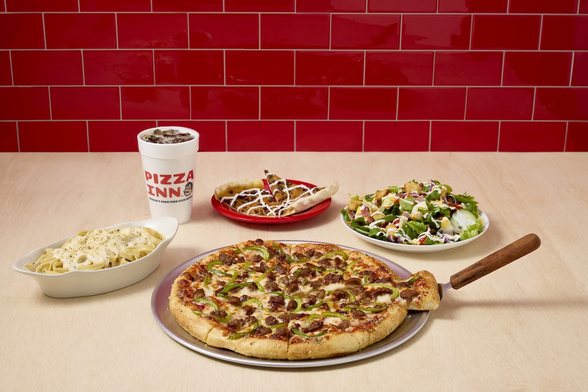 This photo shows a Pizza Inn whole pizza, a dessert pizza, a pasta bowl, a salad and a drink on a white background.