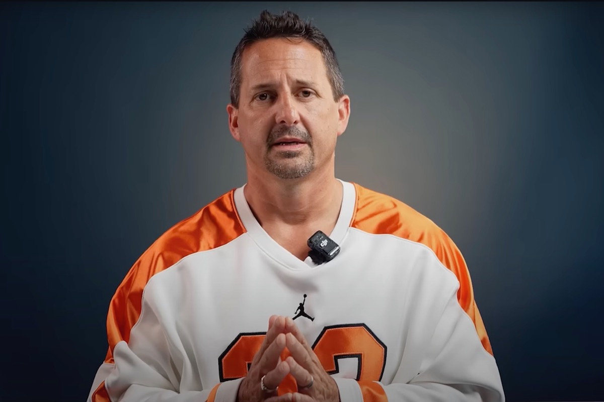This photo shows Matt Plapp in an orange and white jersey looking into the camera with his hands clasped.