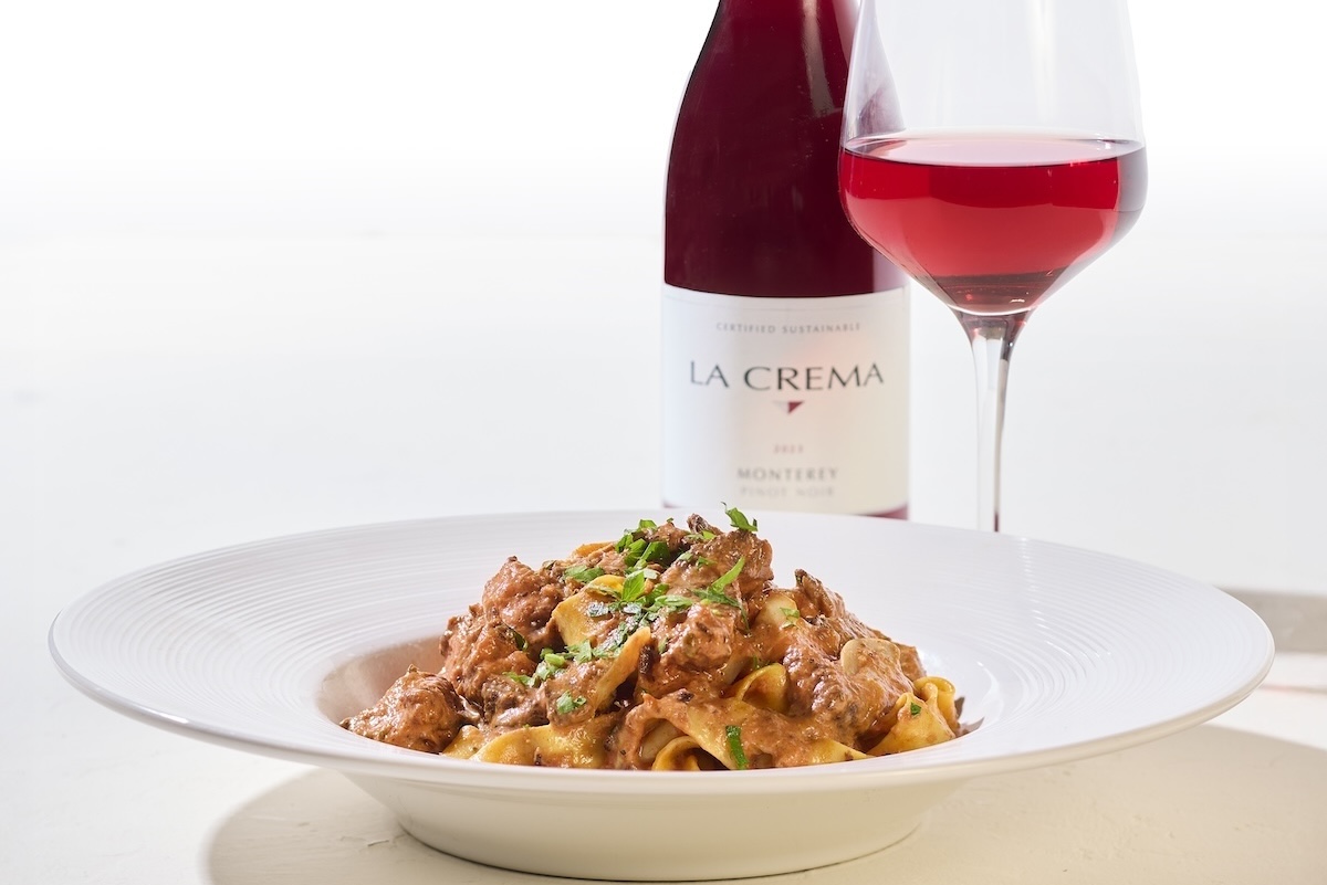 This photo shows a bowl of Braised Short Rib Ragu paired with a glass of red wine.