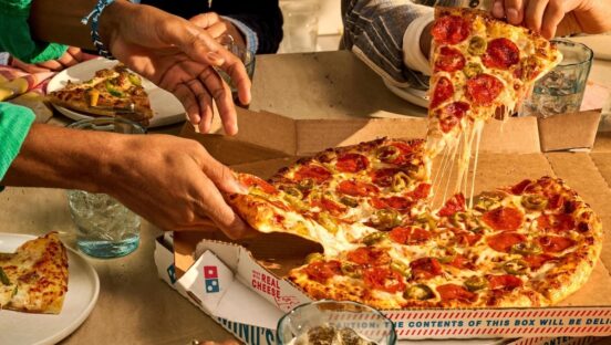 This photo shows customers' hands pulling slices from a hand-tossed Domino's pizza topped with pepperoni.