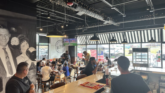 This photo shows the interior of a Leona's Restaurant location with customers eating pizza and sitting at the bar.