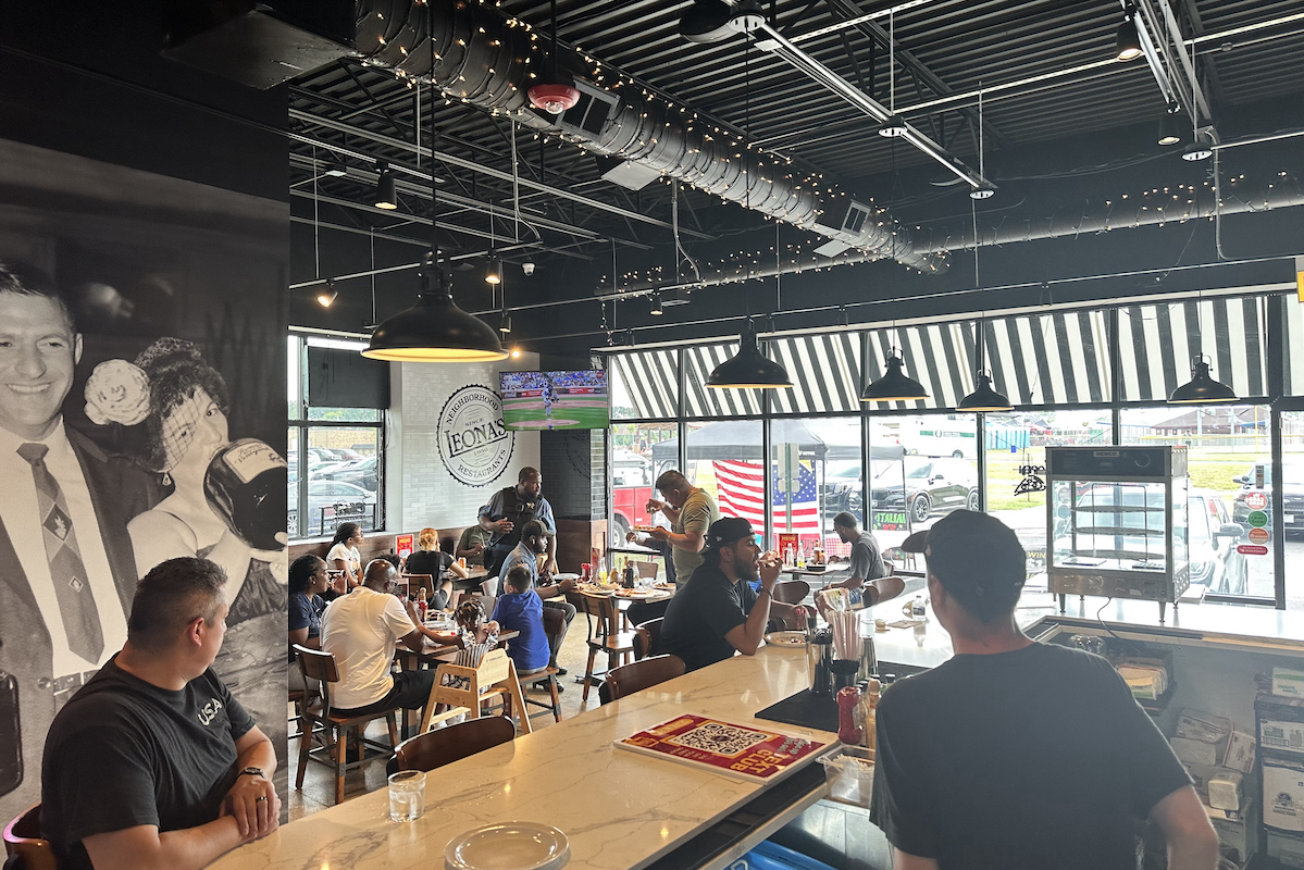 This photo shows the interior of a Leona's Restaurant location with customers eating pizza and sitting at the bar.