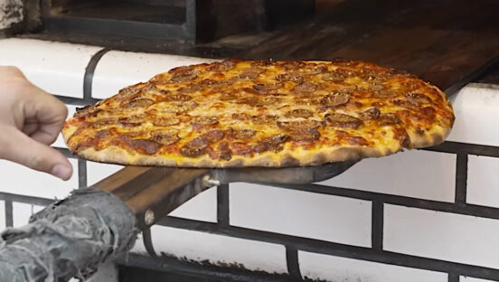 This photo shows the Afterburner pizza, topped with pepperoni, coming out of Frank Pepe's oven.