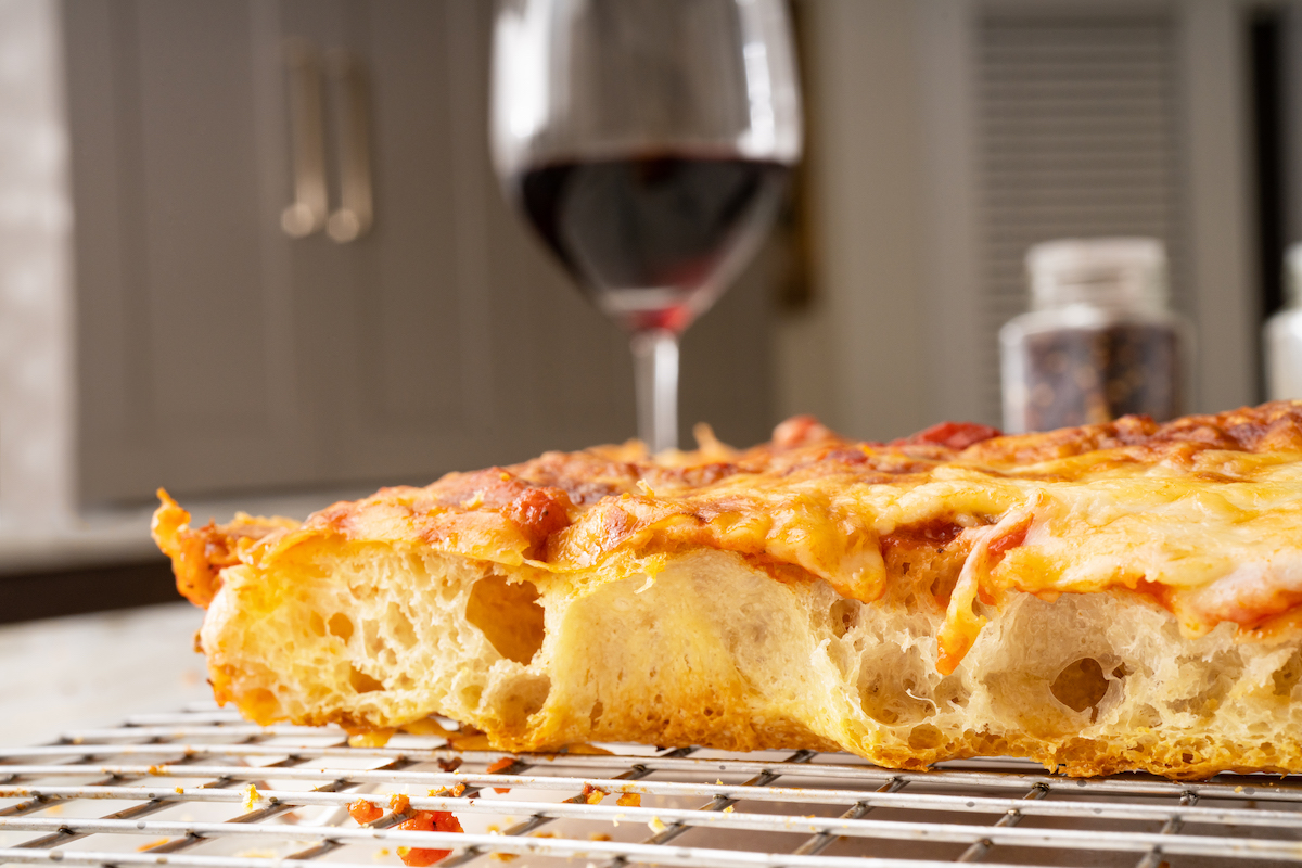 This pizza shows a side view of a baked Pizza Freak Co. cheese pizza, revealing an open crumb structure.