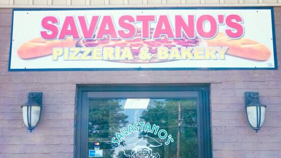 This photo shows the overhead sign and entrance of the pizzeria named in the article.