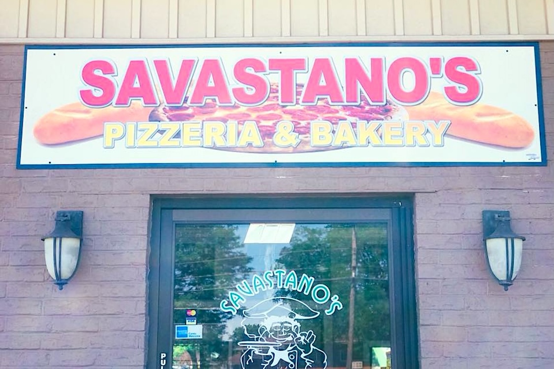 This photo shows the overhead sign and entrance of the pizzeria named in the article.