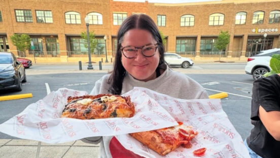 This photo shows a female customer holding paper plates with two slices of pizza from Slice House.