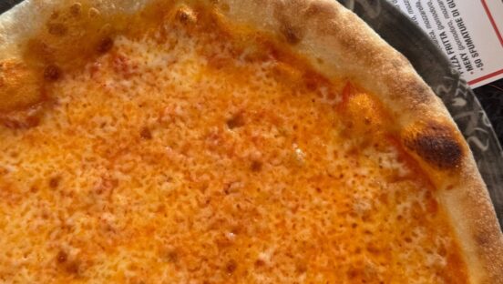 This photo shows the top half of a cheese pizza.