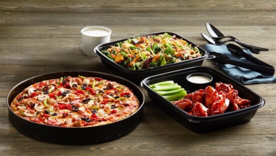 This photo shows a deep-dish pizza in a pan, plus an order of chicken wings and a salad.