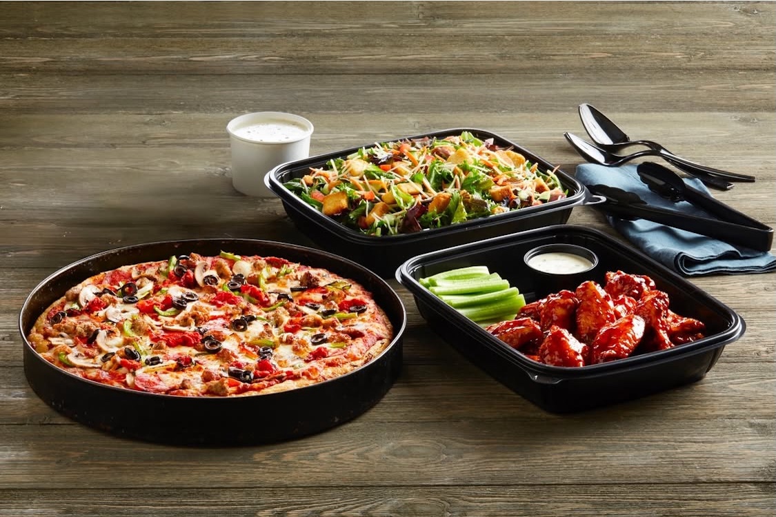 This photo shows a deep-dish pizza in a pan, plus an order of chicken wings and a salad.