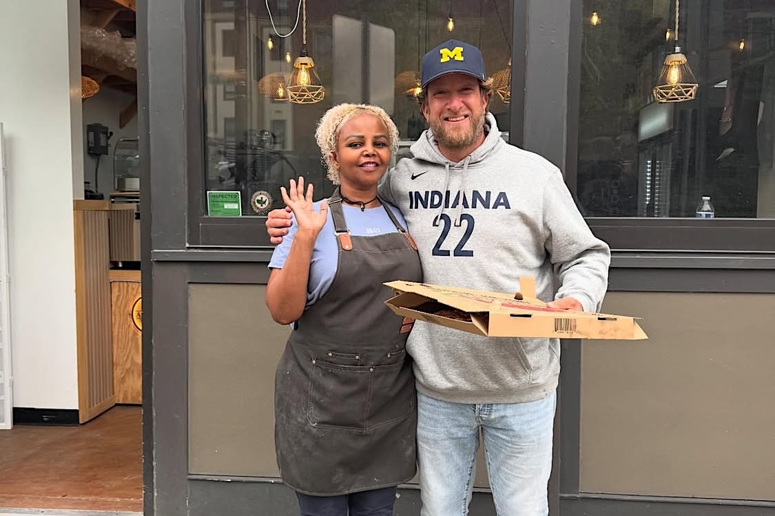 This photo shows Dave Portnoy in front of Artisan Pizza Cafe with his arm around owner Jasmin Ahmed.
