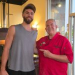 This photo shows Tore Trupiano, in a red chef coat, posing with a member of the San Diago Clippers in his restaurant.