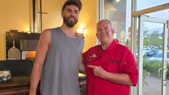 This photo shows Tore Trupiano, in a red chef coat, posing with a member of the San Diago Clippers in his restaurant.