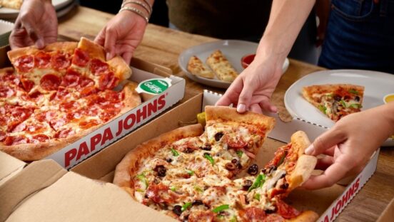 This photo shows customers' hands removing slices from two different pizzas in a delivery box from Papa Johns.