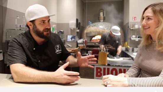 This photo shows Riccardo La Rosa in a black chef coat having a sit-down chat with Erica D'Arcangelo.