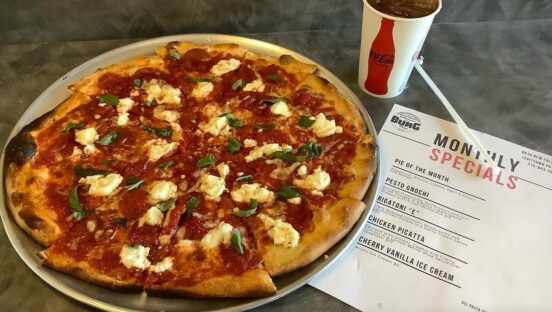 This photo shows a tomato pie next to a menu from DeLorenzo's The Burg