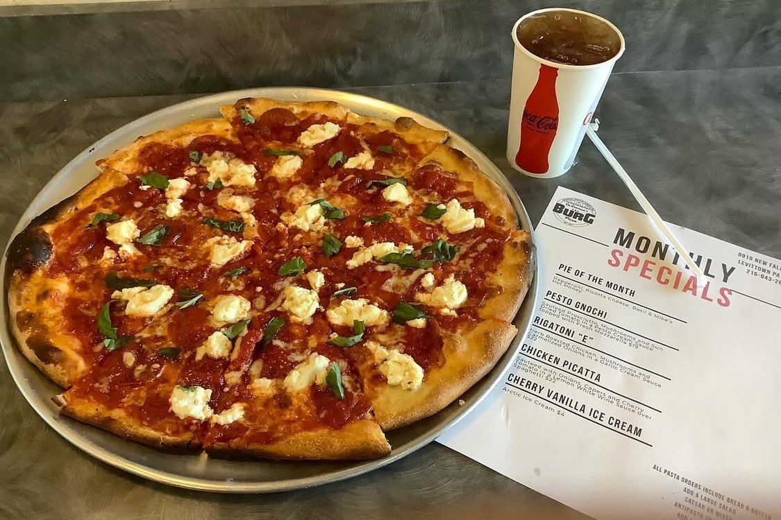 This photo shows a tomato pie next to a menu from DeLorenzo's The Burg