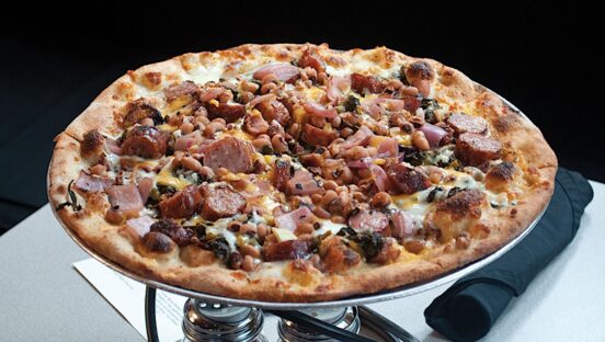 This photo shows the Soul Pie topped with various cheeses plus collard greens, sausage and black-eyed peas.