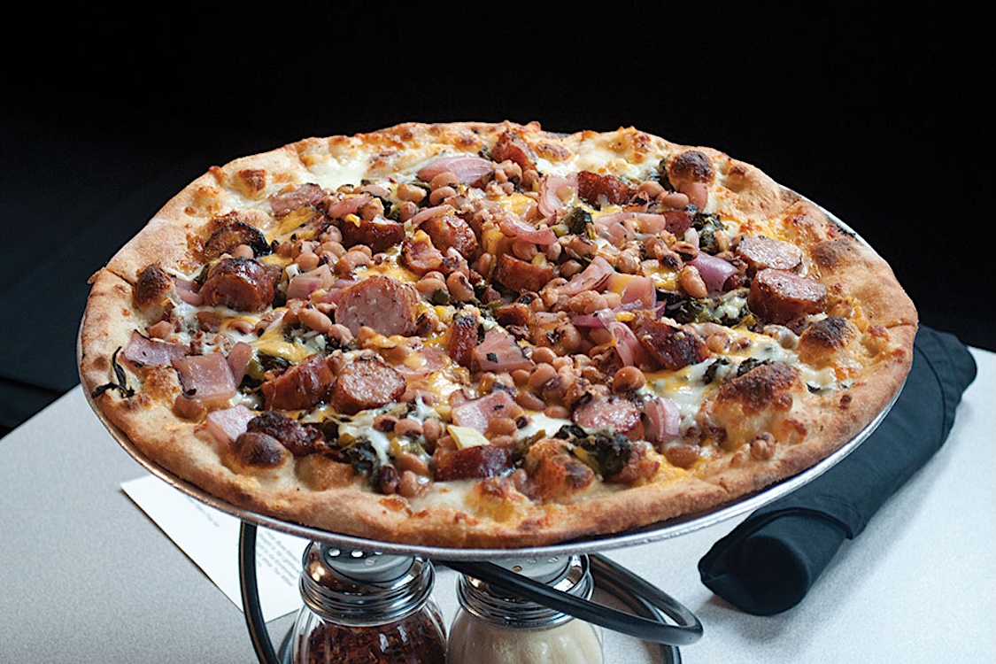 This photo shows the Soul Pie topped with various cheeses plus collard greens, sausage and black-eyed peas.