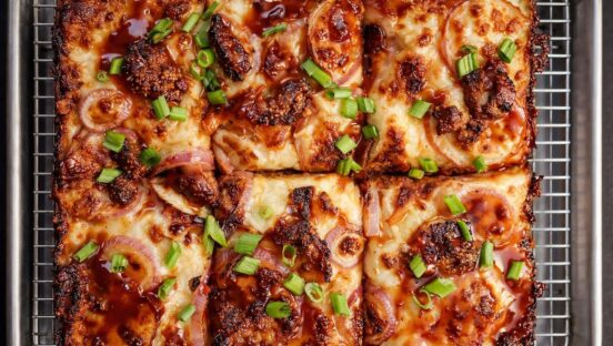 This photo shows a beautiful Detroit-style pizza topped with fried chicken, scallions and Mambo sauce.