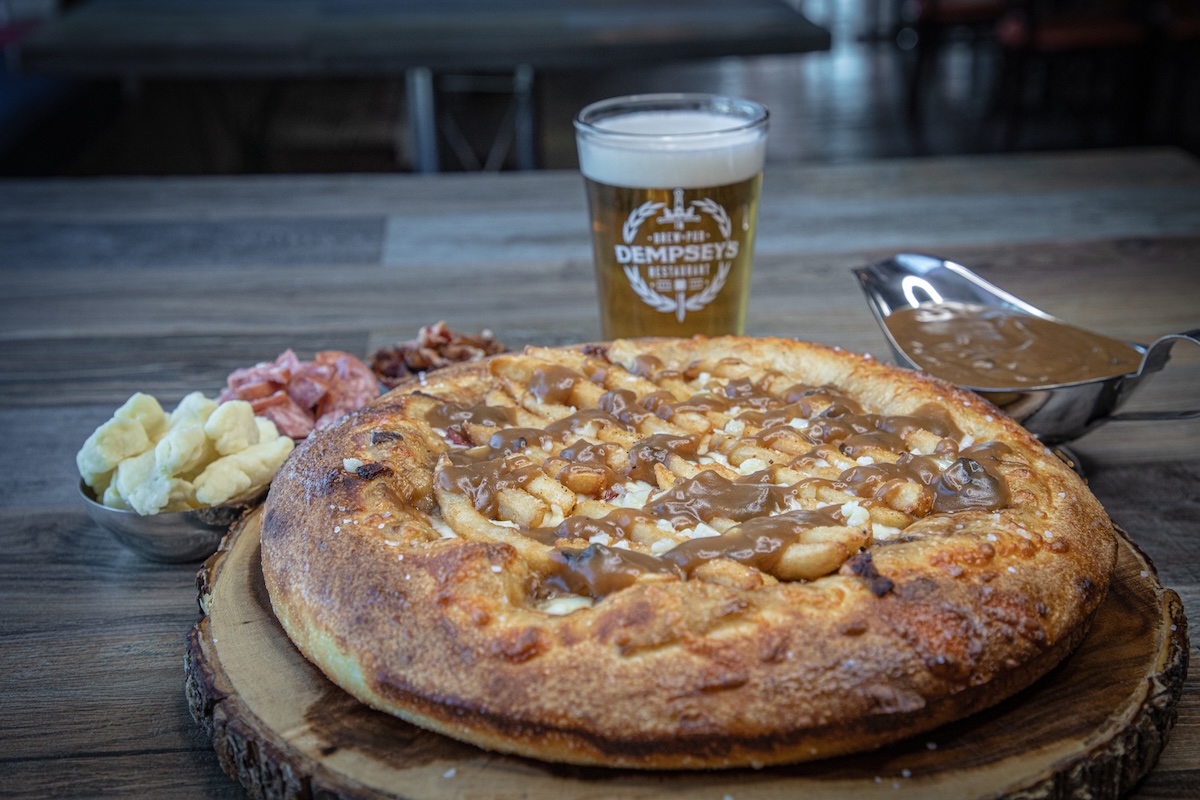 This photo shows a pizza called From Saskatoon With Love topped with French fries, sausage, gravy and more.