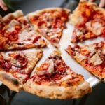 This photo shows a Hawaiian pizza topped with ham, red peppers and pineapple.