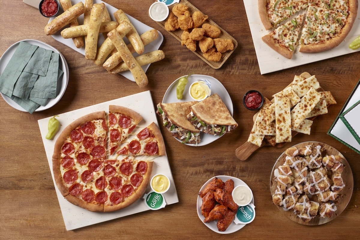 This photo shows a variety of Papa Johns' menu items, including a pepperoni pizza, breadsticks, Papadillas, chicken wings and more.