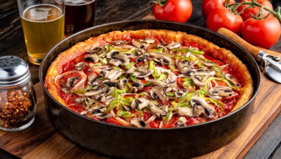 This photo shows a beautiful deep-dish pizza topped with pepperoni, mushrooms and green peppers.