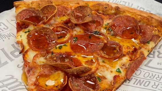 This photo shows a pepperoni pizza on a piece of paper.