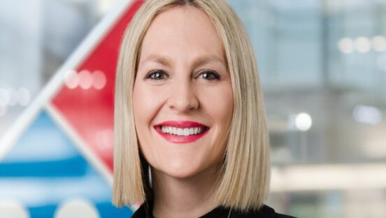 This photo shows a smiling Kate Trumbull with the Domino's logo behind her.