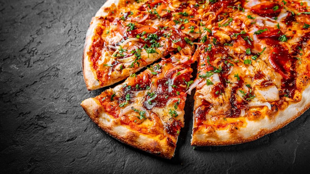 This photo shows a slice pulled out from a whole BBQ chicken pizza.