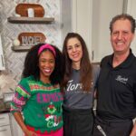 This photo shows the owners of Florish with a local TV show host in the studio kitchen with their arms around each other.