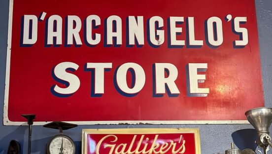 This photo shows a sign that reads D'Arcangelo's Store and beneath it, a second sign that says Galliker's Milk.