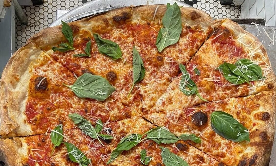 This photo shows a pizza topped with cheese and basil leaves at Mama's Too.