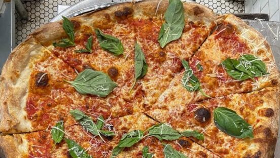 This photo shows a pizza topped with cheese and basil leaves at Mama's Too.