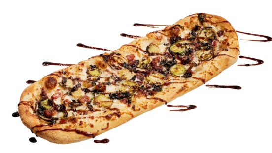 This photo shows a flatbread-style pizza topped with Brussel sprouts and bacon.