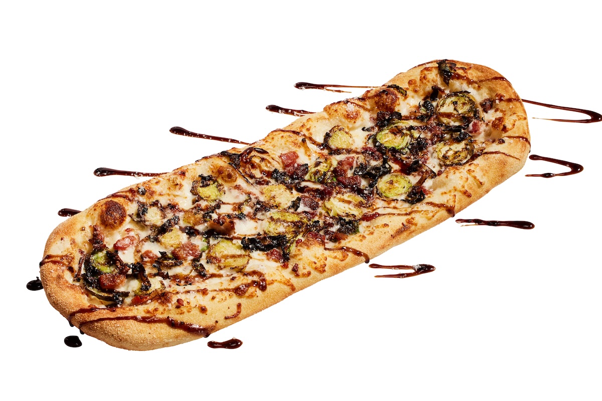 This photo shows a flatbread-style pizza topped with Brussel sprouts and bacon.