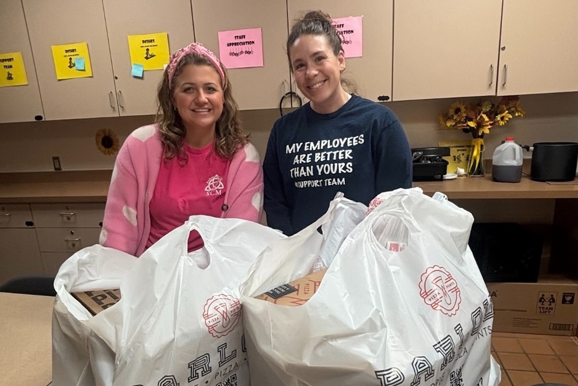 This photo shows two female employees at Parlour with huge bags full of pizzas to be delivered.
