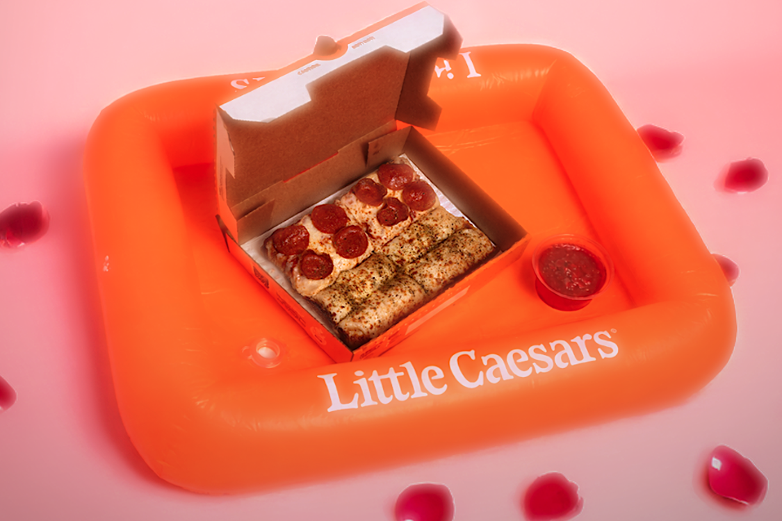This photo shows an open pizza box placed in an orange Little Caesars tub tray.