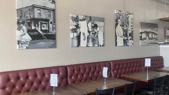 This photo shows the interior of The Original Charlie's Pizzeria with framed vintage photos on the walls above the tables in the dining room.