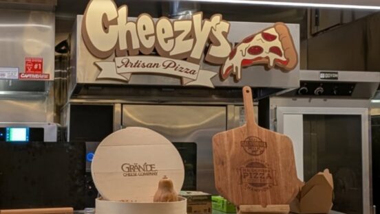This photo shows the interior sign of Cheezy's Artisan Pizza, along with a peel-shaped plaque for winning the Real California Pizza Contest.