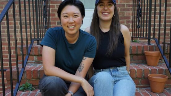 This photo shows Emily Kwak and Christina Cord sitting side by side on the stoop of a house.